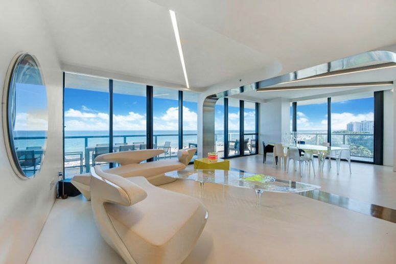 futuristic acrylic coffee table in a living room The dining space is located in the corner, the opposite corner is taken with a sculptural sofa and with a gorgeous acrylic coffee table