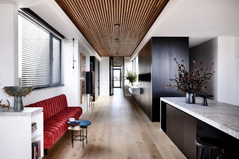 There's a large dark storage unit in the kitchen and a red upholstered bench as a bold touch