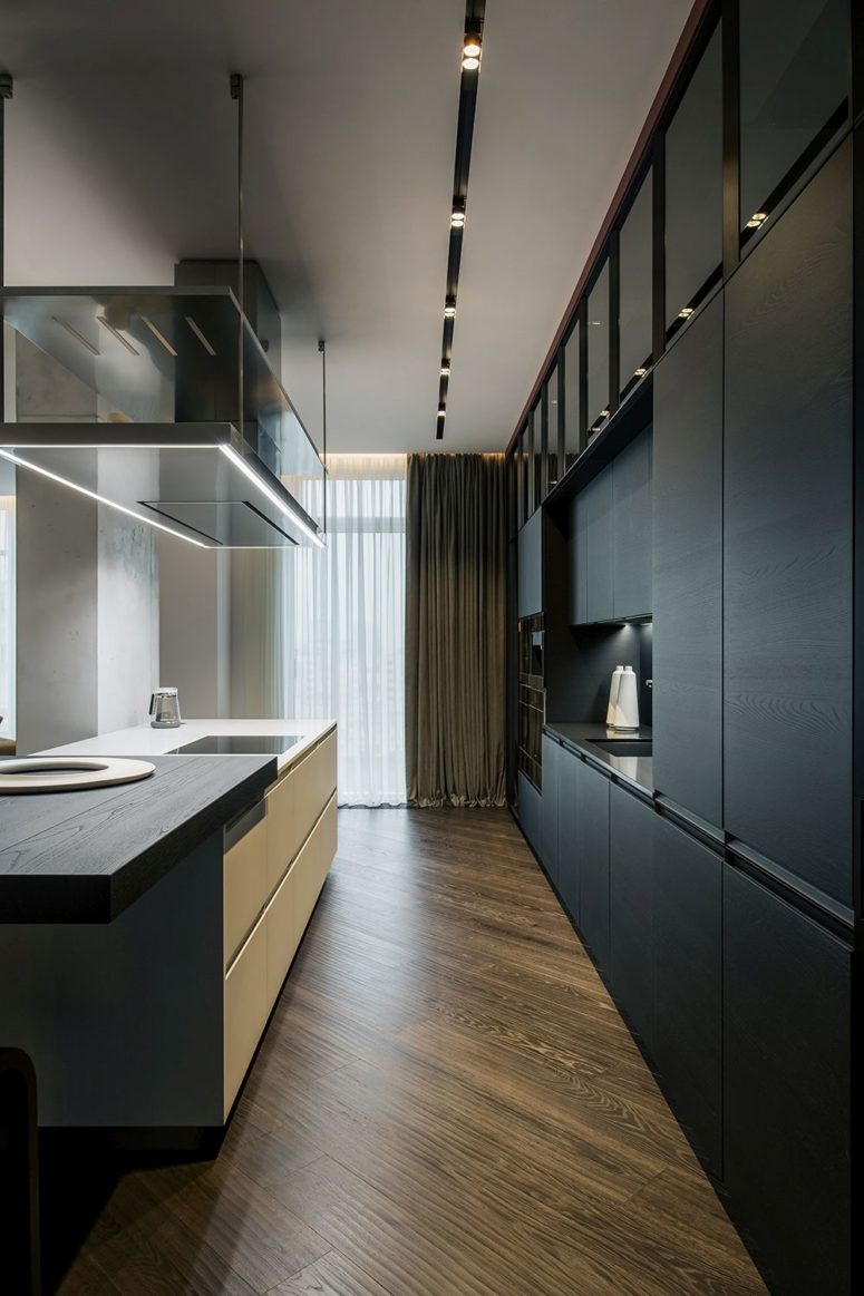 The kitchen is done with sleek black plywood cabinets and a white kitchen island with a plywood countertop The kitchen is done with sleek black plywood cabinets and a white kitchen island with a plywood countertop