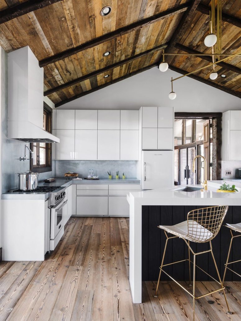 The kitchen is done with sleek white cabinets and a black and white kitchen island plus wooden floors