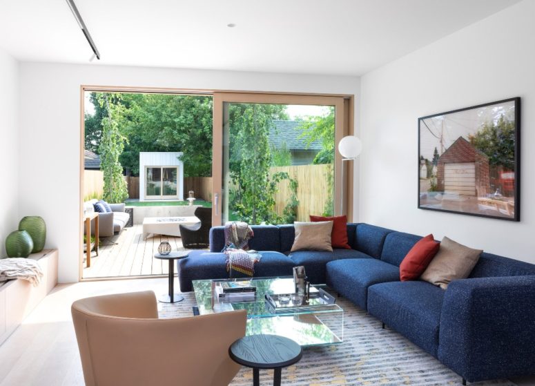 The living room is a united indoor outdoor space with a bold blue corner sofa, catchy furniture and storage items The living room is a united indoor-outdoor space with a bold blue corner sofa, catchy furniture and storage items