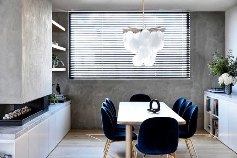 The dining space features contrasting navy chairs of velvet with brass legs