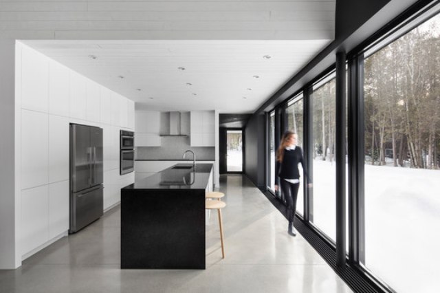 black and white kitchen design The kitchen is large, with white cabinets and a black kitchen island plus panoramic views of the surroundings