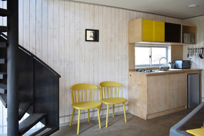There's a kitchen clad with plywood and done with colorful skee panels, and here you can see a staircase leading upstairs