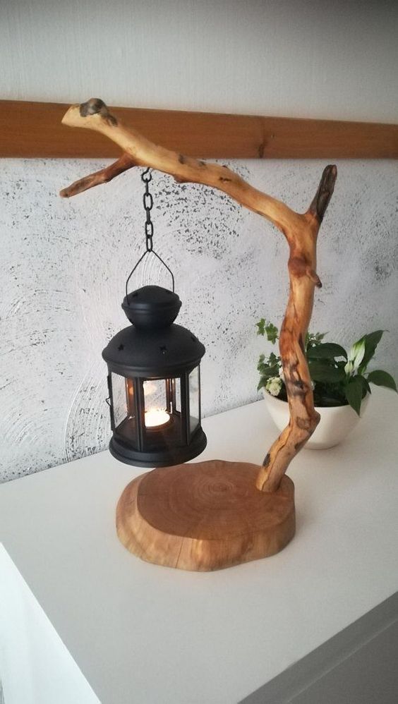 a quirky table lamp made of a wood slice base, a branch and a candle lantern for a cozy and fun touch to your space