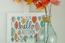 05 a stylish display with a sign, some fall leaves in a clear vase and a candle in opaque glass