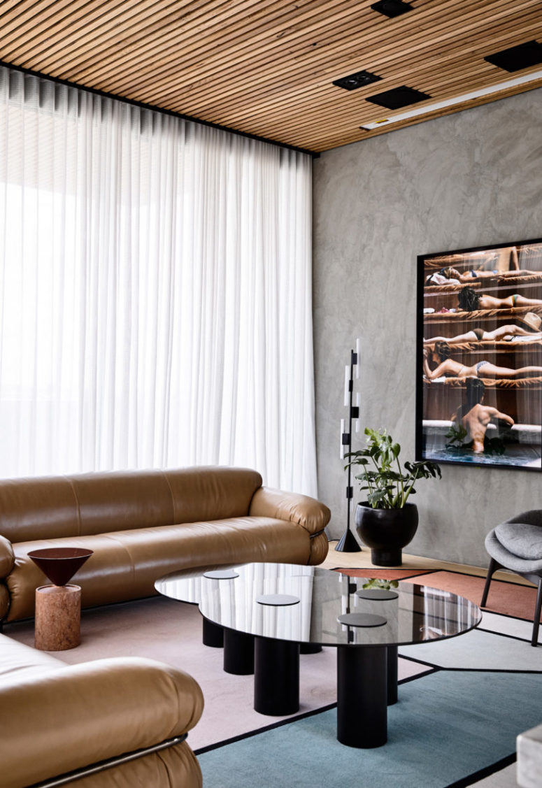 The living room is done with comfy brown leather furniture, catchy tables, pots and artworks