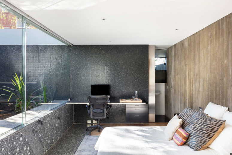 The master bedroom shows off dark stone and tile walls, a weathered wood wall and a comfy bed plus a working space The master bedroom shows off dark stone and tile walls, a weathered wood wall and a comfy bed plus a working space