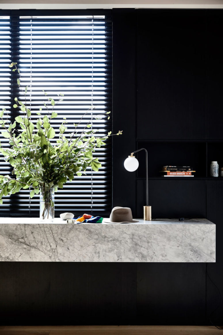 The dark entryway shows off a floating stone vanity with lamps and lights