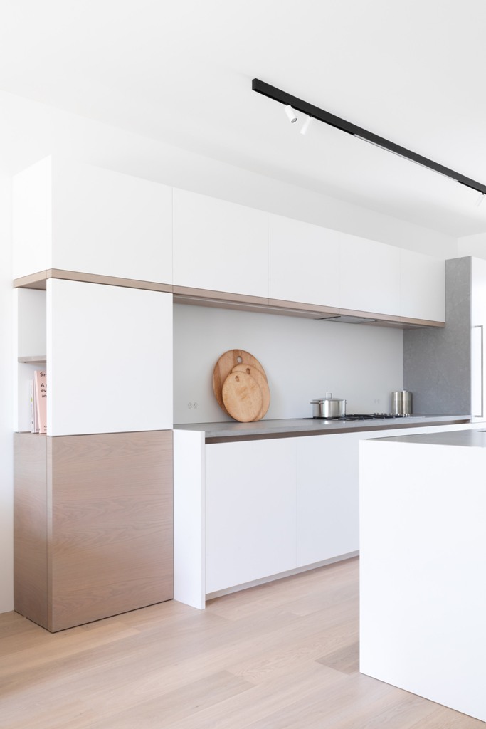 The kitchen is minimalist, in white and beige, with sleek cabinets and a concrete backsplash and countertops The kitchen is minimalist, in white and beige, with sleek cabinets and a concrete backsplash and countertops