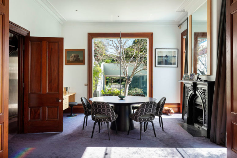 A separate dining room has several floor to ceiling windows, an antique faux fireplace and a large round table with comfy chairs A separate dining room has several floor to ceiling windows, an antique faux fireplace and a large round table with comfy chairs