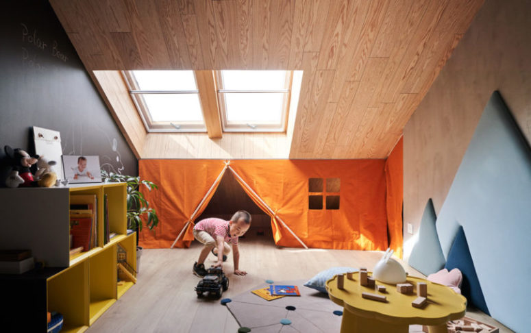 The kid's room features small windows, a plywood covered attic, a chalkboard wall and colorful furniture
