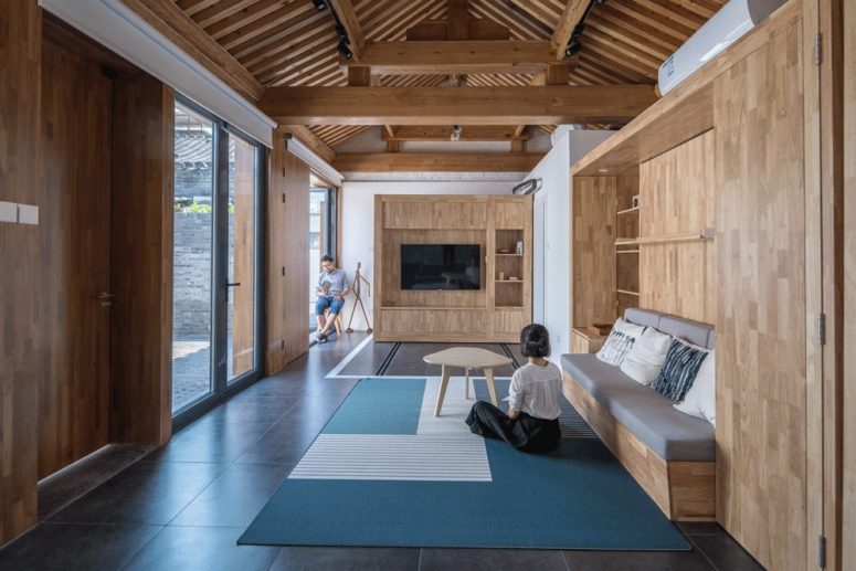 The living room features a bench and a TV unit with shelves plus much negative space for an airy feel