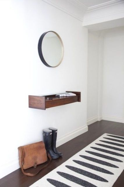 a tiny floating dark-stained wood console and a mirror in a metallic frame for a chic look