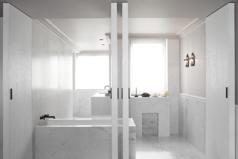 The bathroom is clad with white marble and is highlighted with black fixtures