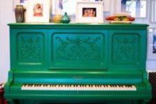 10 a bright emerald piano and stool and a display of family pics over the piano