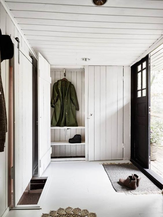 a cozy and simple entryway with whitewashed wood plank walls, ceiling and storage furniture