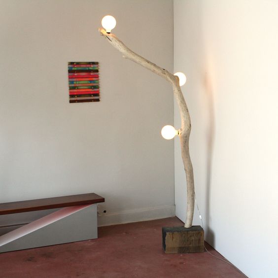 a super creative floor lamp with a wood piece base, a tree branch and some bulbs inserted
