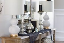 11 a rustic console with a bird, a skull, some spiderweb and black candles in tall candleholders