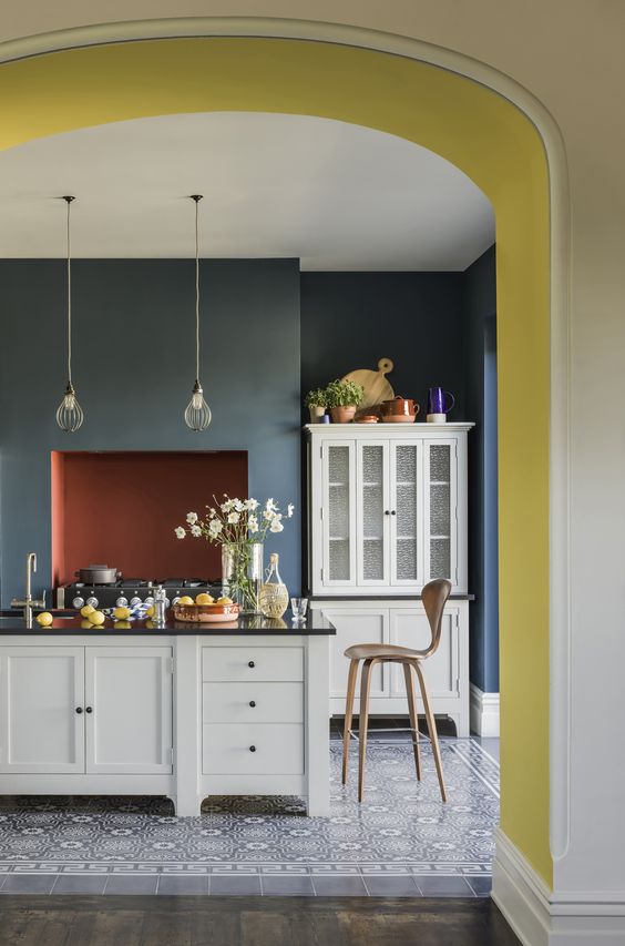 a color block kitchen with yellow, teal and terracotta accents, patterned tiles and white cabinets