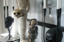 15 a spooky console display with skulls and a mummy plus candles and a haunted scenery on the artwork