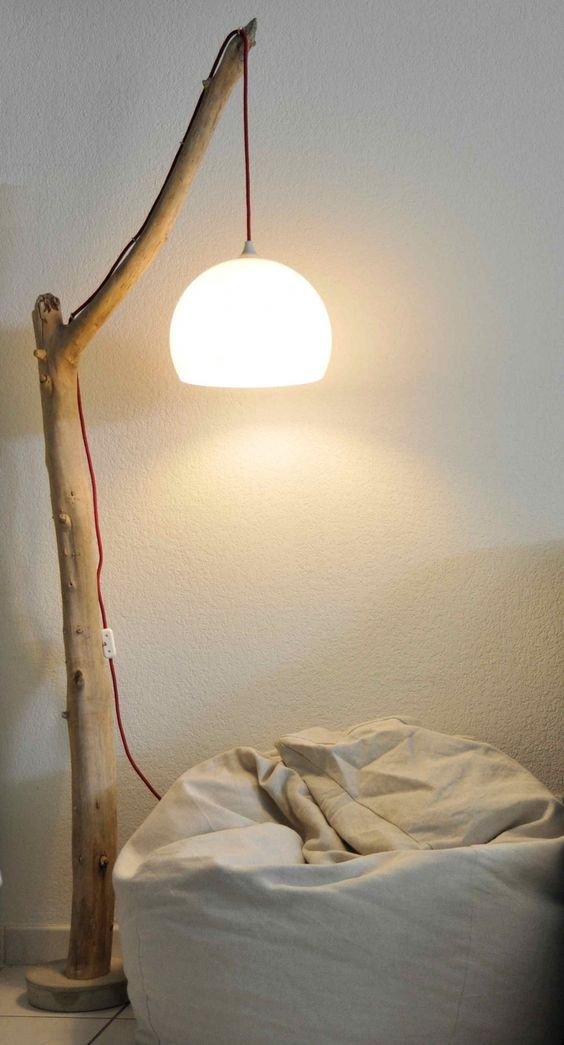 a pendant light hanging on a large tree branch, a red cord contrasts the simple wood look