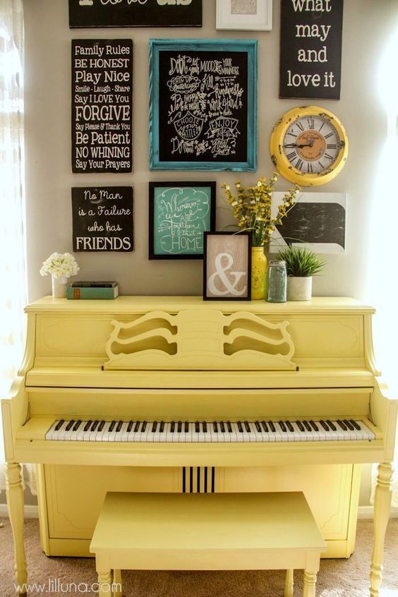 a sunny yellow piano and a matching stool, a gallery wall over the piano with various signs and art