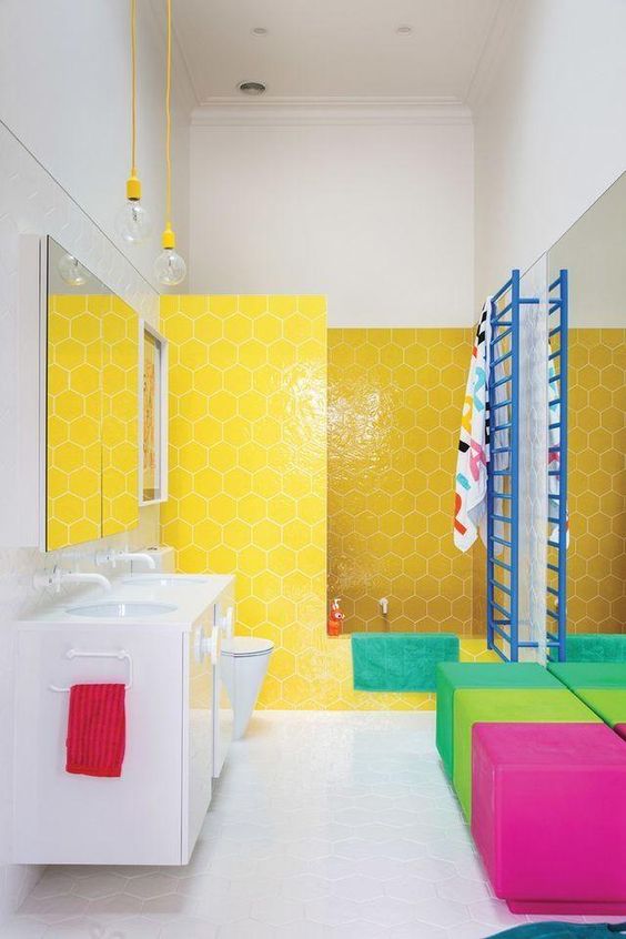 a color block upholstered ottoman plus a yellow hexagon tile wall in the shower make the bathroom stand out