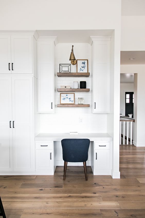a modern farmhouse space with a seamless home office nook with cabinets, built-in shelves and a black chair