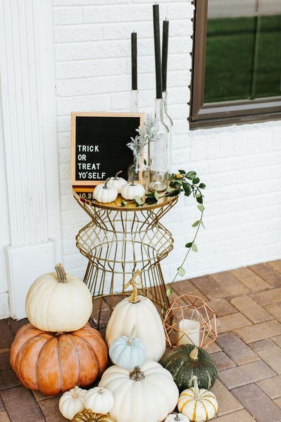 a stylish modern display with lots of pumpkins, geometric lanterns, black candles and a black framed sign
