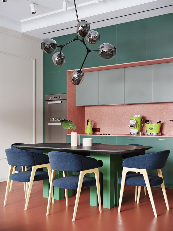 dark green cabinets plus a pink backsplash create bold color blocking, a green table and navy chairs add even more color