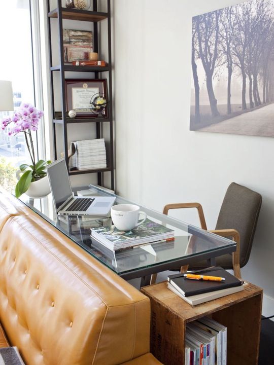 this home office nook uses the blind space behind the sofa, which is usually neglected, and a glass desk makes it airy