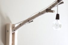 22 a simle natural and industrial wall lamp with a birch branch and a simple bulb on cord