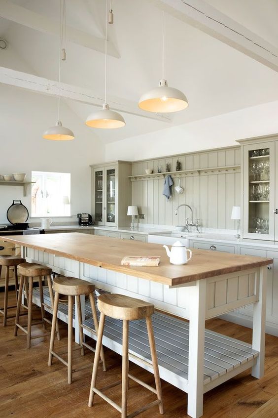a simple and neutral farmhouse space with a large kitchen island and dining table in one with additional storage space