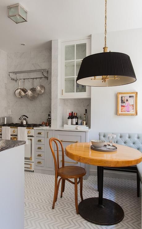 a French kitchen with grey and white cabinets, a corner eating zone with a grey corner bench and a black pendant lamp