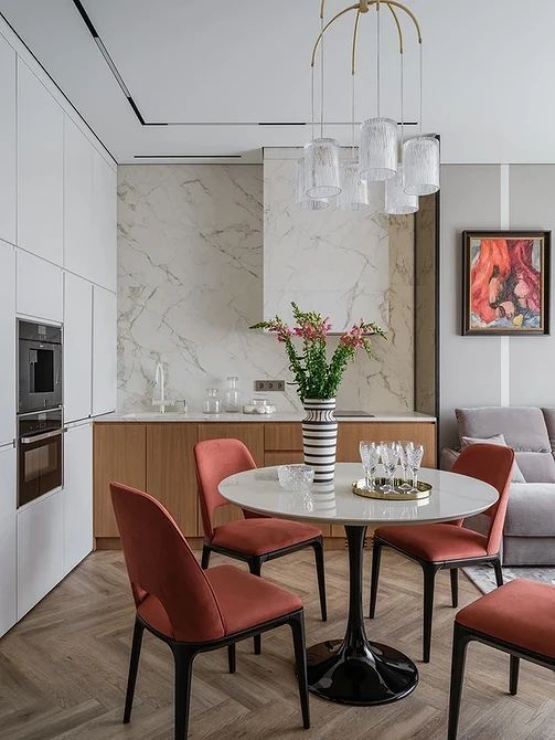 a bright eat-in kitchen with stained cabinets, a white stone backsplash and hood, a round table and red chairs
