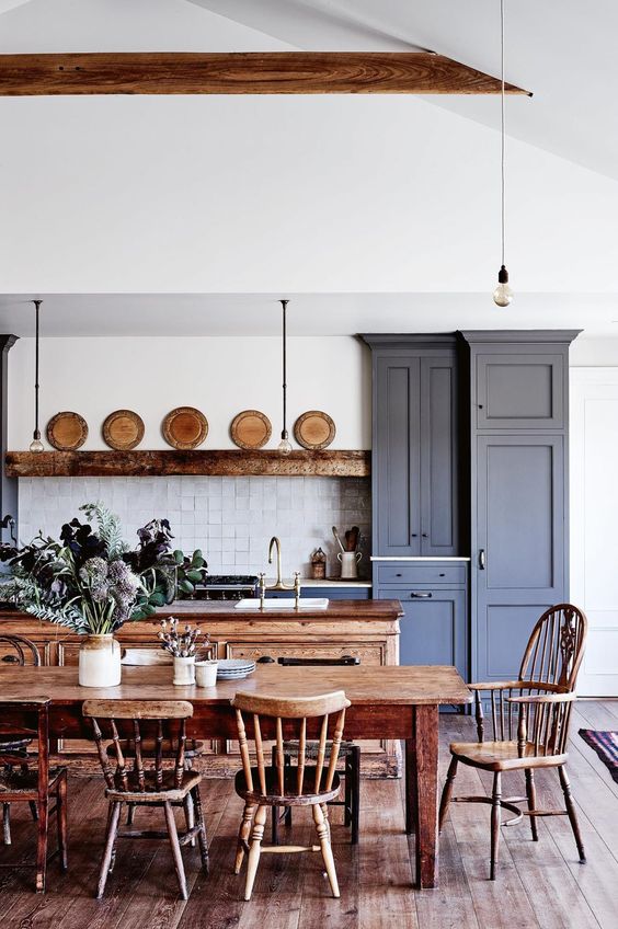 a grey blue farmhouse kitchen with shaker cabinets, a stained kitchen island, a vintage stained dining set