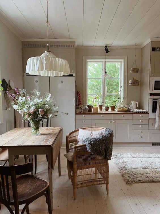a neutral Nordic kitchen with butcherblock countertops and a stained dining set, a pendant lamp over the table