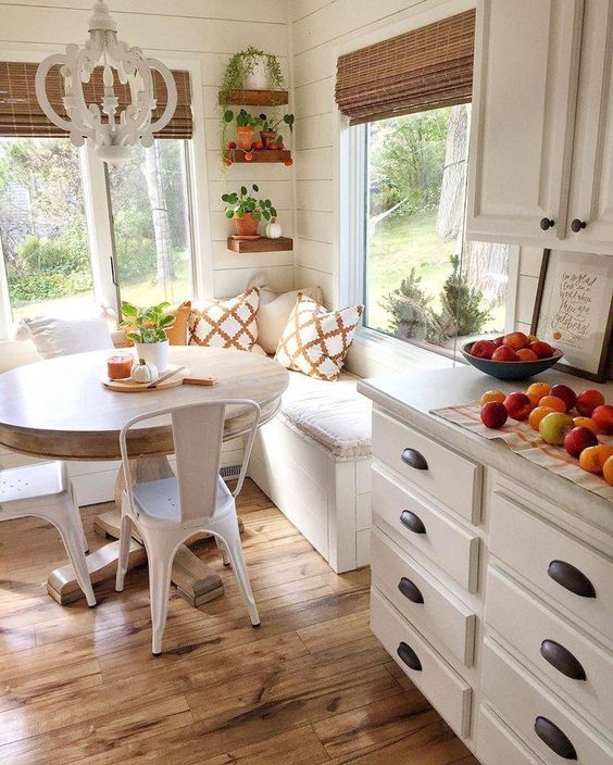 a neutral cottage eat-in kitchen with stone countertops and a dining corner, a corner bench, a round table and metal chairs