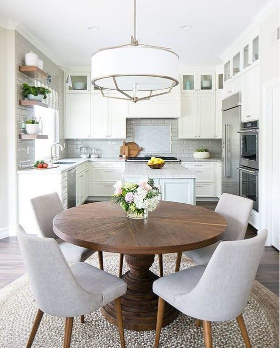 a neutral modern farmhouse kitchen with a pendant lamp, a round table and grey chairs is a very welcoming space