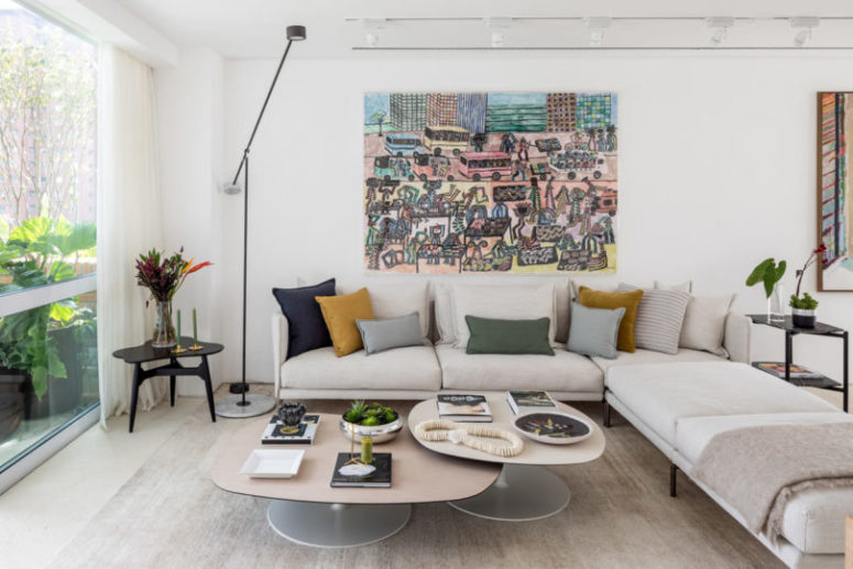 The living room is done with neutrals and colorful touches, it's filled with light through a glazed wall
