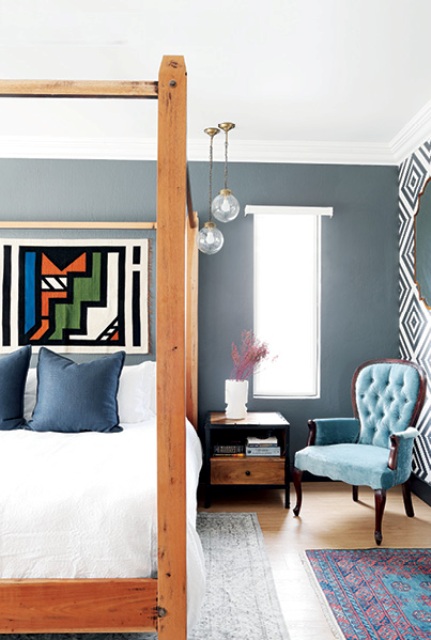 The master bedroom features a large framed bed, some reupholstered furniture and an artwork