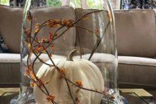 03 a cloche with a single white pumpkin and orange blooms on branches is a classic fall idea