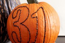 03 a real pumpkin with art made with decorative nails and yarn is an easy Halloween craft