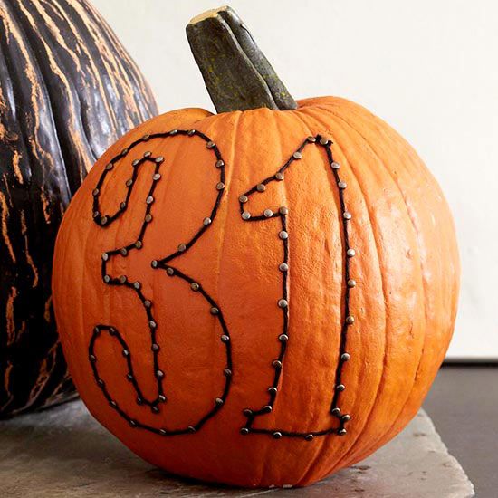 a real pumpkin with art made with decorative nails and yarn is an easy Halloween craft