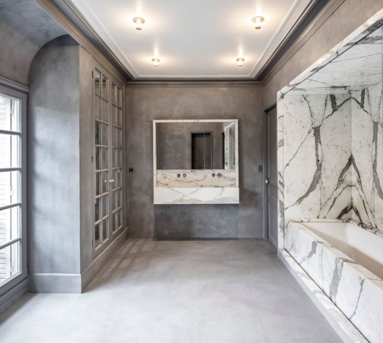 The bathroom is luxurious,done in concrete and marble, with French doors, windows and a bathtub