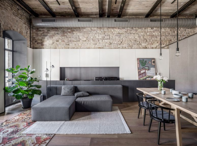 The dining space shows off a wooden table, black chairs and minimalist geometric furniture plus much closed storage