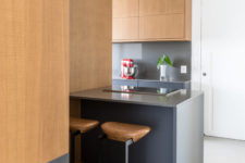 04 The kitchen features sleek grey surfaces and wood for a contrast, there’s a kitchen island with a breakfast nook