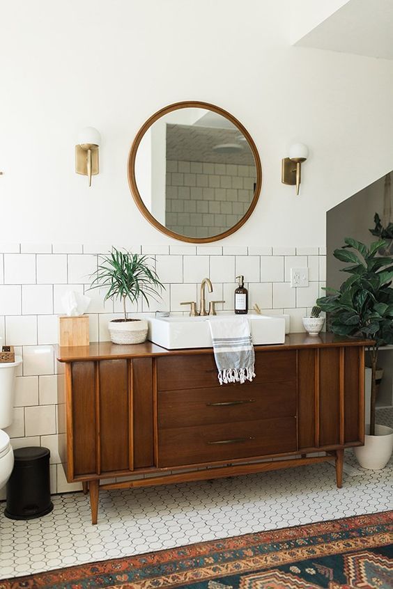 a mid-century modern bathroom with subway tiles, a wooden vanity and much potted greenery