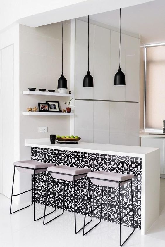 an all-white minimalist kitchen enlivened with bright black and white printed tiles on the kitchen island